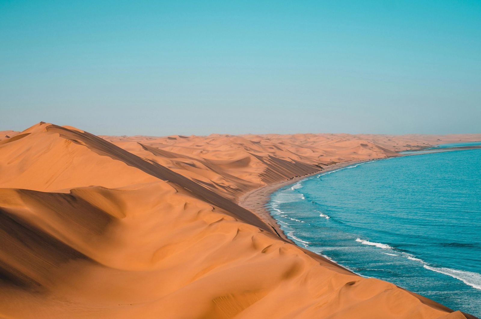 A 4x4 crossing a red Namibian dune with the ocean beyond